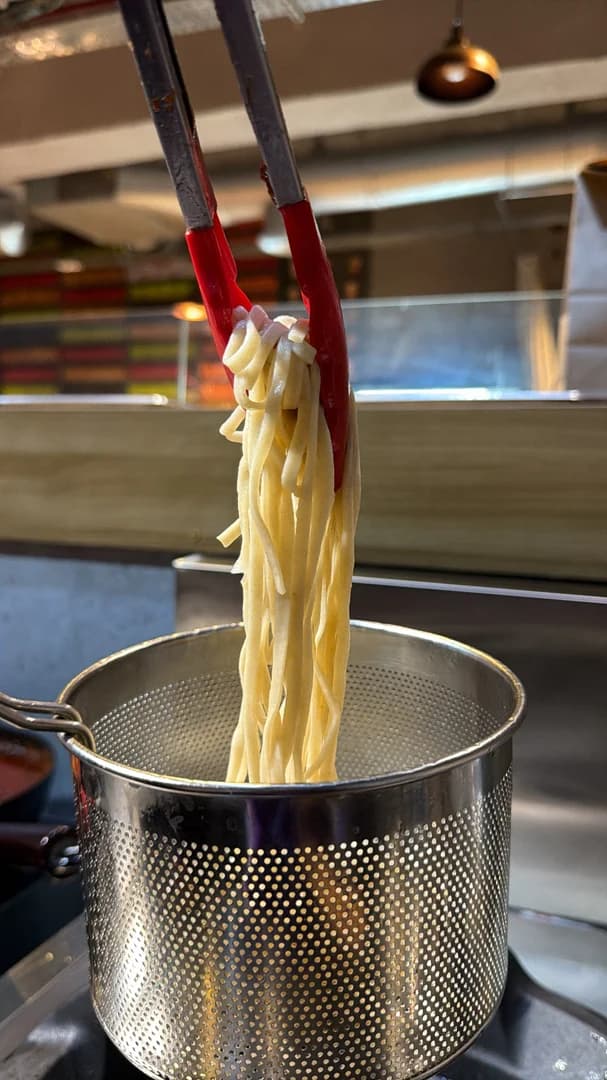Hands making fresh handmade ramen noodles.